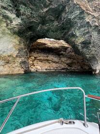 A stunning view of a natural rock arch over turquoise waters, showcasing the beautiful coastline — perfect for exploring hidden gems while boating.