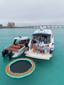 A lively group gathers on a luxurious boat, enjoying a day on the water with a floating mat nearby — perfect for celebrations and group outings.