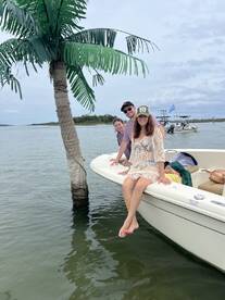 A cheerful group enjoys their time on a boat, posing playfully with a palm tree backdrop — perfect for memorable outings on the water.