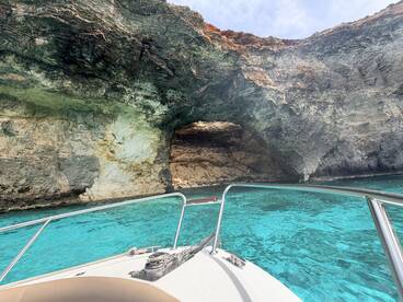 A stunning view of a natural cave along the coastline, captured from the bow of a boat in crystal-clear turquoise waters — perfect for exploring scenic destinations.