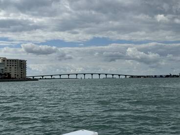 A scenic view of a bridge spanning over tranquil waters, framed by a cloudy sky — perfect for capturing the beauty of coastal landscapes.