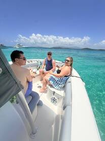 A cheerful group enjoys their time aboard a boat in crystal-clear waters, perfect for snorkeling and relaxation under the sun.