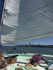 A scenic view from a sailboat featuring a picnic setup on deck, with the iconic bridge in the background — perfect for a relaxing day on the water.