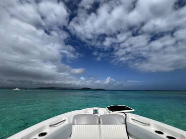 A stunning view from the front of a speedboat, showcasing crystal-clear turquoise waters and a dramatic sky — perfect for a day of adventure on the water.