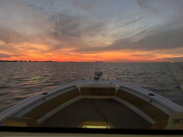 A stunning sunset view from the bow of a boat, showcasing vibrant colors over the water — perfect for evening cruises.