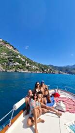A cheerful group enjoys a sunny day on a boat, soaking in the stunning coastal views — perfect for memorable outings and celebrations on the water.