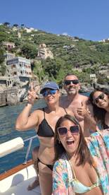 A joyful group of friends poses for a fun selfie on a boat, with stunning coastal scenery in the background — perfect for memorable summer adventures.