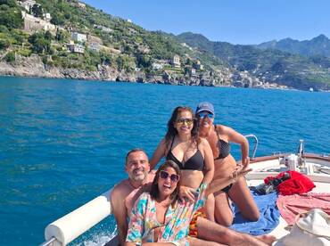 A joyful group of friends enjoys a sunny day on a boat, showcasing the stunning coastline in the background — perfect for memorable outings and celebrations on the water.