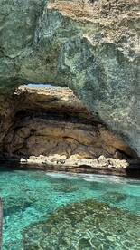 A stunning view of a natural cave along the coastline, with crystal-clear turquoise waters reflecting the sunlight — a perfect destination for exploration and adventure.