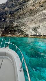 A stunning view of a boat navigating through crystal-clear turquoise waters, showcasing the beautiful rocky coastline — perfect for exploring hidden gems on the water.