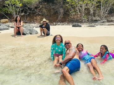 A joyful family enjoys a fun day at the beach, playing in the shallow water and creating lasting memories together.