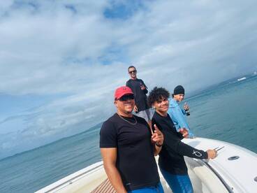A group of friends enjoys a day on the water, posing on the boat while fishing — perfect for creating unforgettable memories on a fishing trip.
