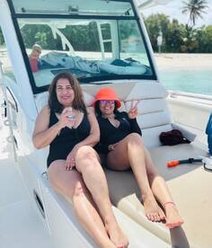 Two friends enjoy a sunny day on a boat, relaxing and celebrating with drinks — perfect for a fun day out on the water.