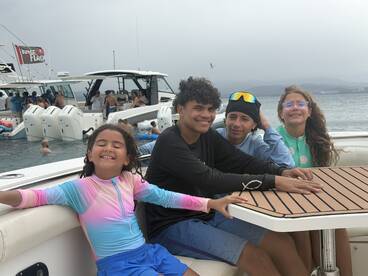 A joyful group of kids and teens relaxes on a boat, enjoying their time together on the water — perfect for family outings and summer adventures.