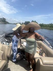 Two women enjoy a sunny day on a boat, showcasing a fun and relaxed atmosphere perfect for summer outings.