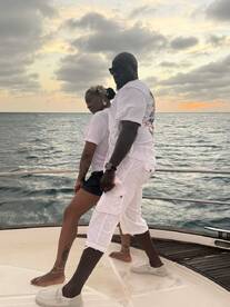 A couple poses against a stunning sunset backdrop on a yacht, capturing a moment of joy and romance on the water.