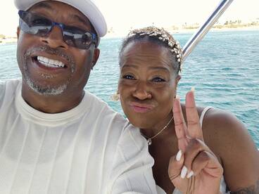 A joyful couple takes a selfie on a boat, capturing a memorable moment of celebration on the water.