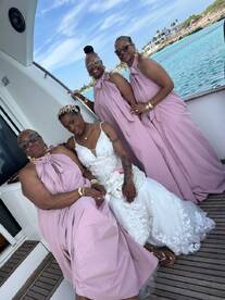 A joyful group of women celebrates a wedding aboard a boat, showcasing elegant dresses and a beautiful backdrop of turquoise waters — perfect for memorable wedding moments.
