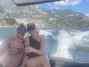 A couple enjoys drinks while cruising on a boat, surrounded by stunning coastal scenery — perfect for romantic getaways or fun outings on the water.