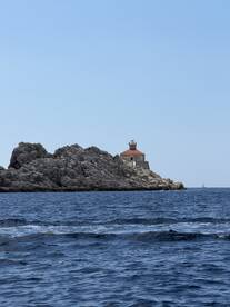 A picturesque view of a lighthouse perched on rocky cliffs, surrounded by tranquil waters — a stunning landmark perfect for boat tours and scenic cruises.