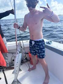 A young man proudly displays his catch while fishing on a boat, showcasing the thrill of a successful fishing trip.
