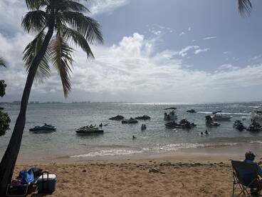 A vibrant scene at the beach with multiple jet skis and people enjoying water activities — a perfect day for fun in the sun.