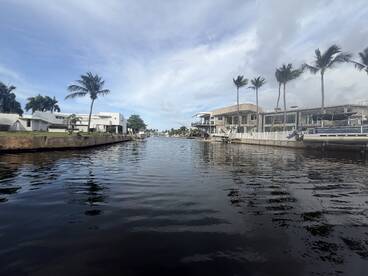 A view of a canal lined with palm trees and waterfront properties, showcasing a serene waterway scene.