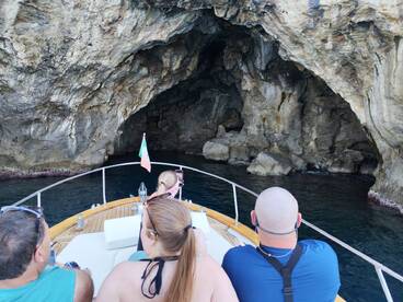 A group of guests enjoys a scenic boat ride exploring a stunning cave, capturing the adventure on their phones. Perfect for those seeking unique experiences on the water.