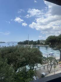 A picturesque view of a harbor with sailboats anchored, framed by lush greenery and a clear blue sky — a perfect representation of a serene coastal getaway.