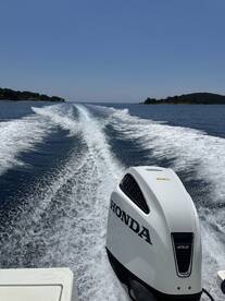 A dynamic view of a Honda outboard motor cutting through the water, showcasing the thrill of speed on a sunny day.