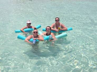 A fun group of friends enjoys a refreshing day in the water, floating with drinks in hand — perfect for a summer getaway or beach party.
