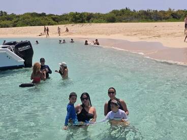 A joyful family enjoys a fun day at the beach, swimming in crystal-clear waters near a sandbar, creating unforgettable memories under the sun.