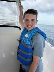 A cheerful child wearing a life jacket aboard a boat, ready for a fun day on the water. Perfect for family adventures and safety on the sea.