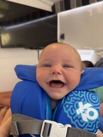 A joyful baby wearing a life jacket smiles brightly, capturing the excitement of a fun day on the water. Perfect for family boating adventures.