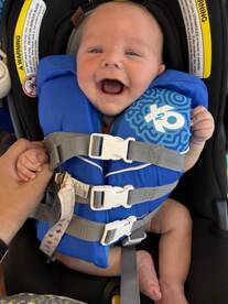 A joyful baby in a life jacket, ready for a boating adventure. Safety first for little ones on the water!