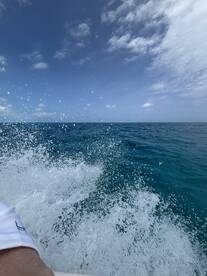 An unclear image capturing splashes of water with a view of the ocean and sky, lacking identifiable subjects or context.