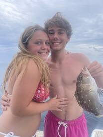 A joyful couple proudly displays their catch while enjoying a fishing trip at sea — a perfect moment of celebration and adventure on the water.