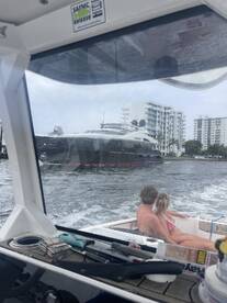A couple enjoys a scenic view from their boat as a luxurious yacht passes by, capturing the essence of a perfect day on the water.