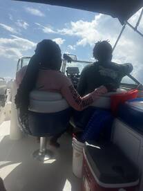 Two individuals enjoy steering a boat under a bright sky, capturing the essence of a fun day on the water.