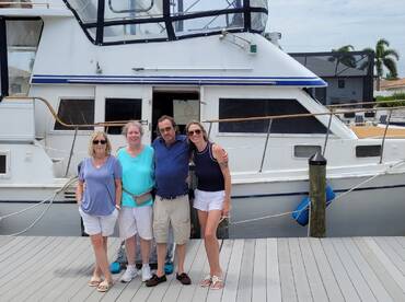 A cheerful group poses together in front of a boat, capturing a memorable moment at the dock — perfect for family gatherings or celebrations on the water.