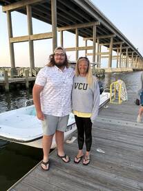 A cheerful group poses together on the dock next to their boat, capturing a memorable moment before heading out on the water.