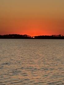A serene sunset over the water, creating a picturesque backdrop perfect for evening boat cruises.