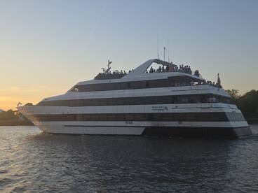 A lively scene aboard a cruise ship as guests enjoy the sunset on the water, perfect for memorable outings in Boston Harbor.