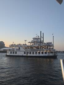 A scenic view of a boat filled with guests enjoying a sunset cruise, creating a perfect backdrop for celebrations on the water.