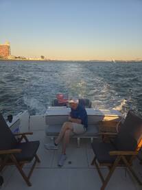 A man relaxes on the deck of a boat, enjoying the scenic views of the water and shoreline — a perfect moment for unwinding on the water.