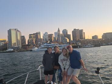 A family enjoys a scenic sunset view from their boat, with a stunning city skyline in the background — perfect for memorable outings on the water.