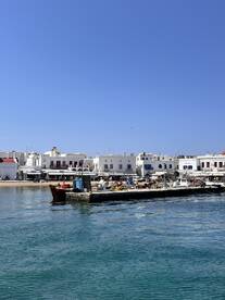 A picturesque view of a boat navigating through calm waters near a charming harbor, showcasing the vibrant coastal architecture in the background.