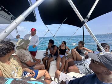 A lively group enjoys a boat tour, engaging with the captain while taking in the beautiful ocean views — perfect for memorable adventures on the water.