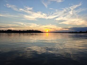 A stunning sunset reflects on calm waters, creating a picturesque scene perfect for evening boat trips and relaxation.