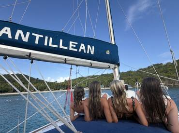 A group of friends enjoys a scenic view from the back of a sailboat, capturing the essence of a perfect sailing adventure.